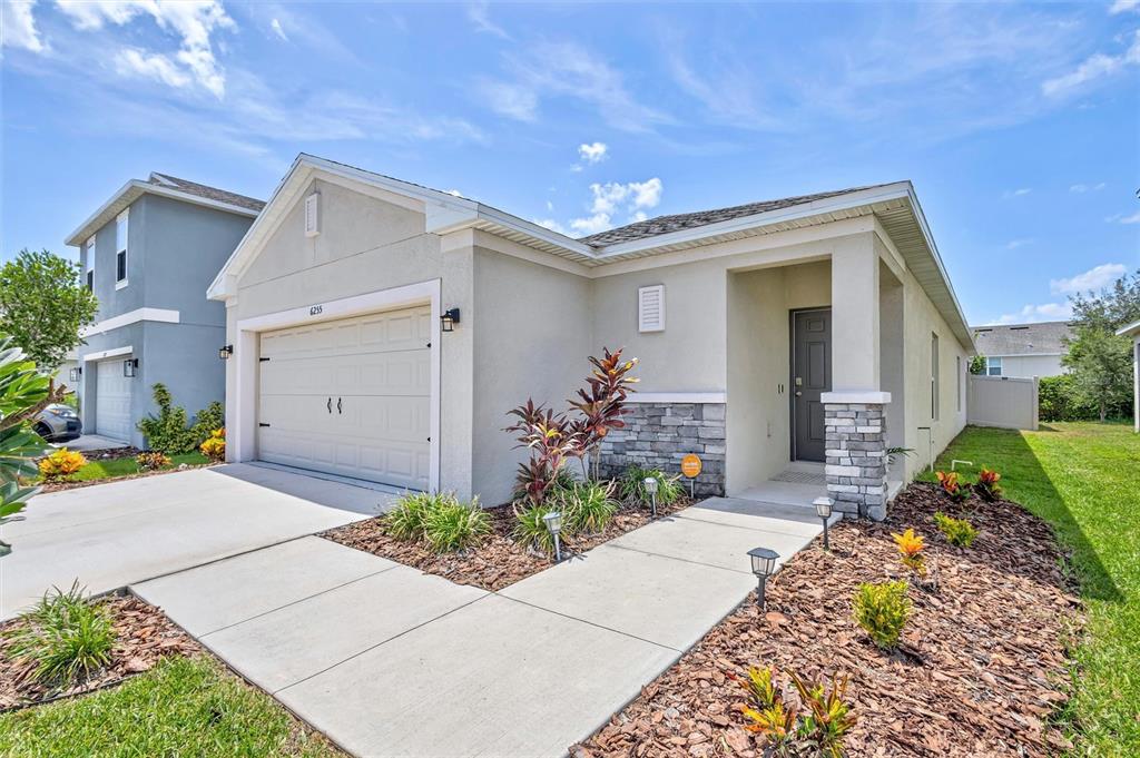 A single-story house with a beige stucco exterior, stone accents, and a concrete driveway — 6255 SPRINGMONT LOOP, PALMETTO, FL
