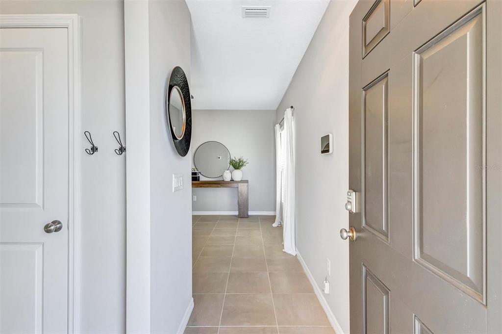 An entryway with tile flooring leads to a hallway featuring a console table and mirror — 6255 SPRINGMONT LOOP, PALMETTO, FL