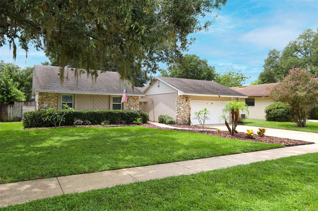 A single-story house with a stone facade, a white garage door, and a grassy front lawn — 2450 CANTERCLUB TRAIL, APOPKA, FL