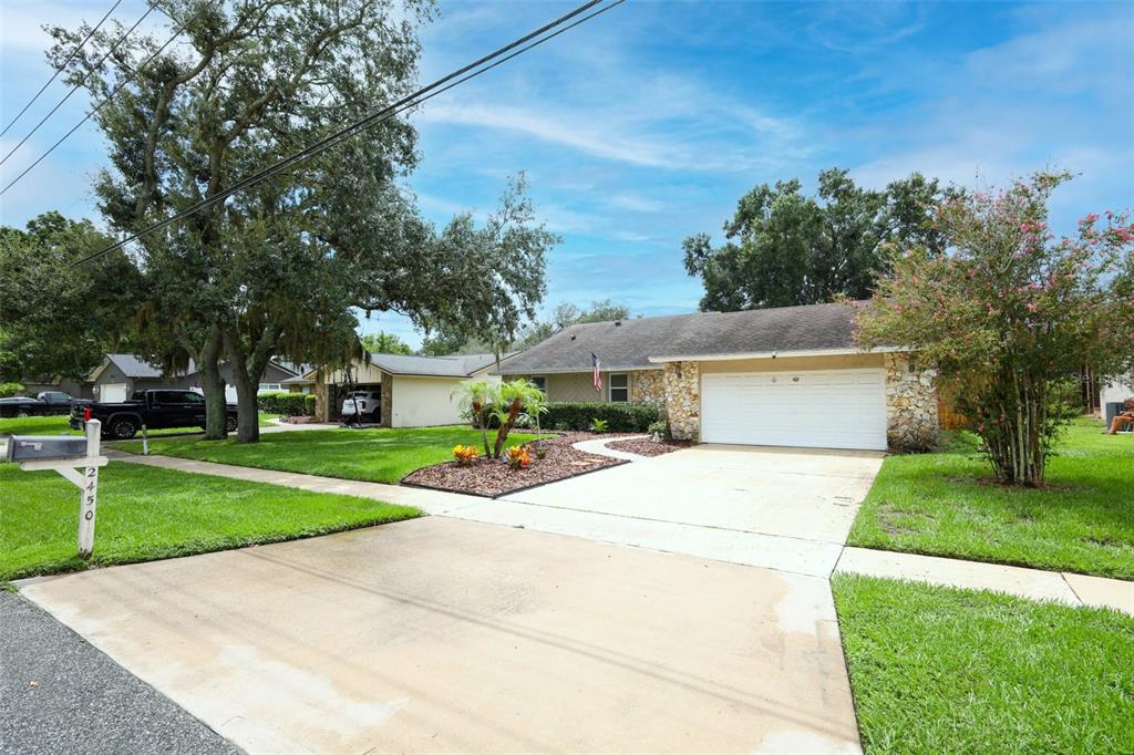 A single-story house with a stone facade, a two-car garage, and a concrete driveway — 2450 CANTERCLUB TRAIL, APOPKA, FL