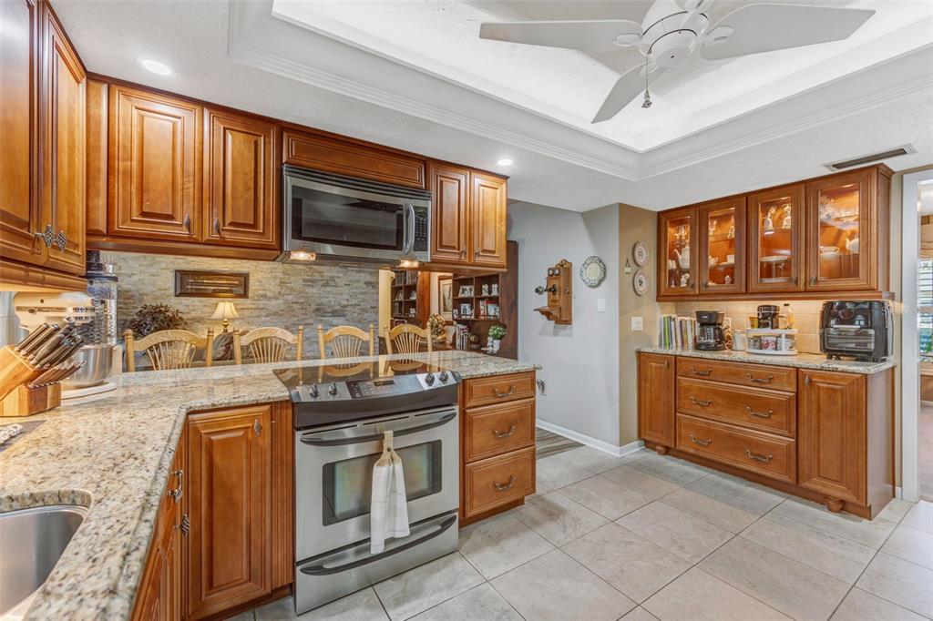A kitchen features wood cabinets, granite countertops, stainless steel appliances, and a tile floor — 4001 HIGHGATE DRIVE, VALRICO, FL