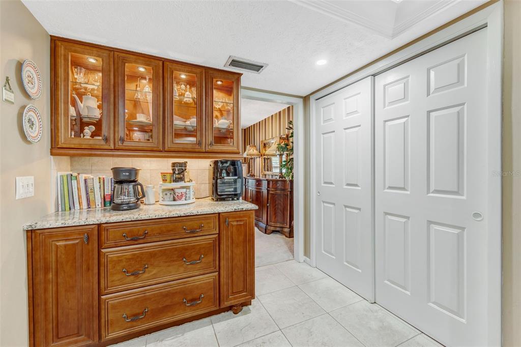 A kitchen coffee station with wood cabinets, granite countertops, and white sliding closet doors — 4001 HIGHGATE DRIVE, VALRICO, FL