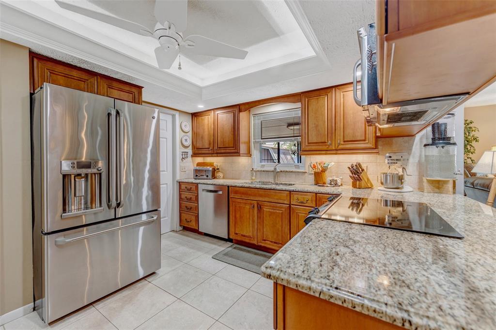A kitchen with wood cabinets, granite countertops, stainless steel appliances, and a ceiling fan — 4001 HIGHGATE DRIVE, VALRICO, FL
