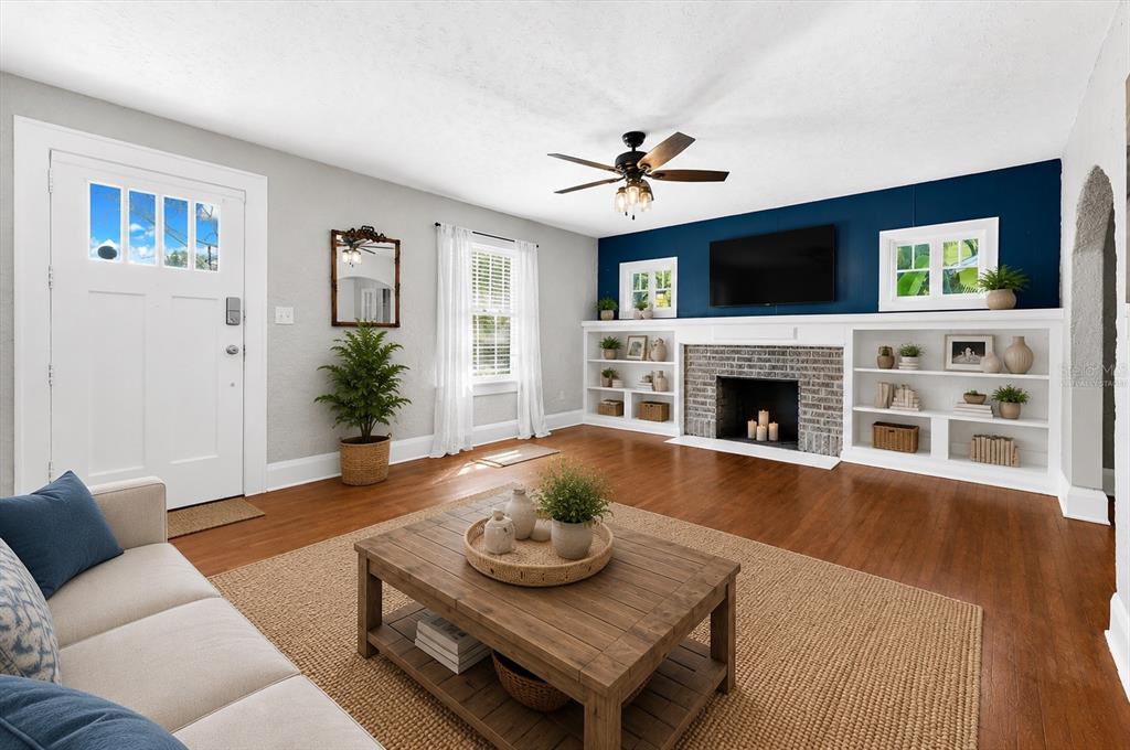 A living room features a fireplace, built-in shelving, a blue accent wall, and hardwood floors — 2726 8TH AVENUE W, BRADENTON, FL