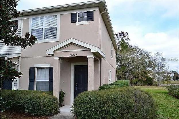 A two-story tan house with a covered entryway and dark shutters on the windows — 15647 STABLE RUN DRIVE, SPRING HILL, FL