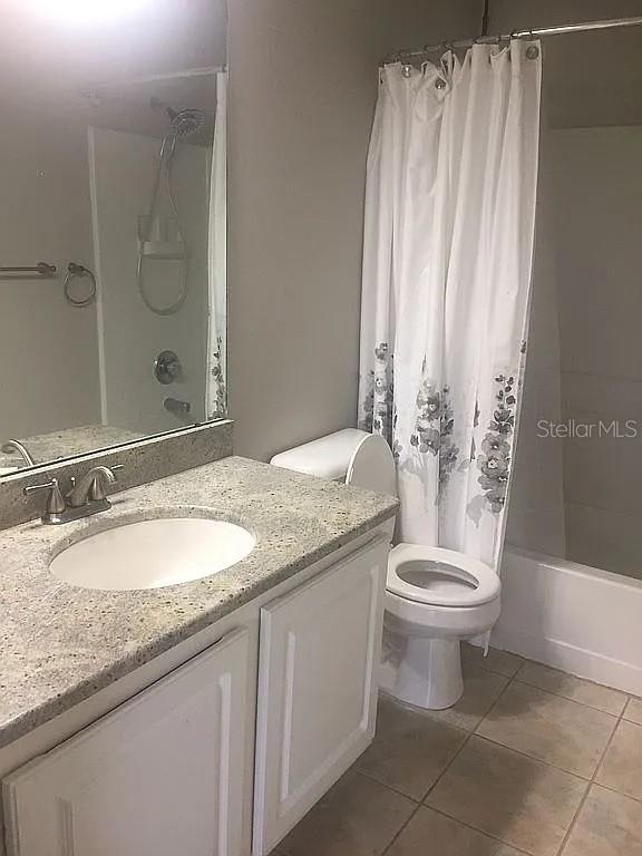 A bathroom features a granite vanity, a white toilet, and a shower with a curtain — 15647 STABLE RUN DRIVE, SPRING HILL, FL
