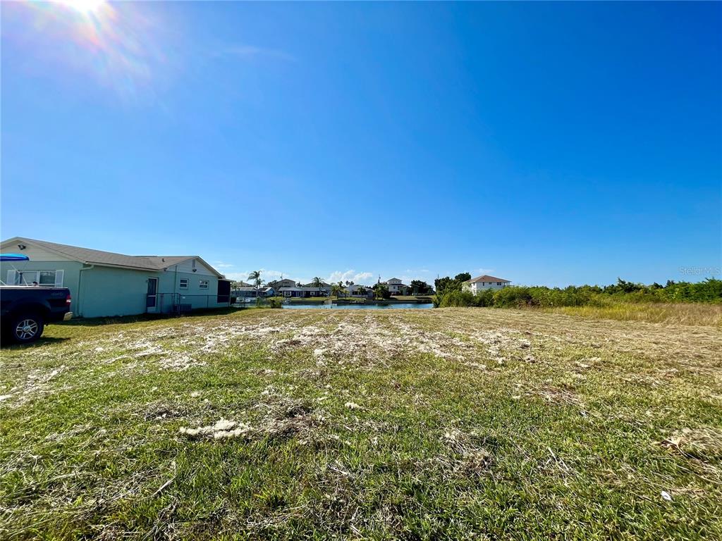 A grassy vacant lot sits next to a house with a view of a canal — 0 POINSETTIA DRIVE, HERNANDO BEACH, FL