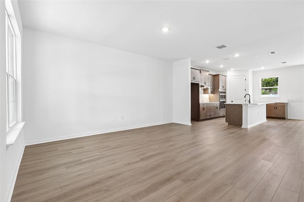 An open-concept living area with light wood-look flooring and a kitchen with dark cabinetry — 4272 DARBY COURT, EUSTIS, FL