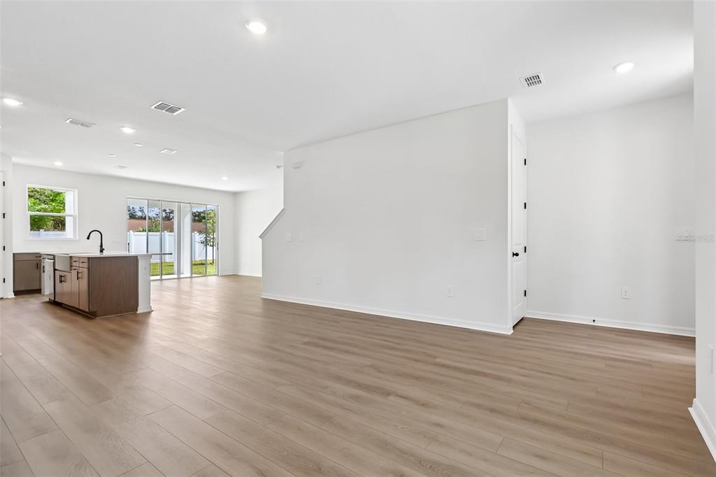 An open-concept living area features light wood-look flooring, white walls, and a modern kitchen island — 4272 DARBY COURT, EUSTIS, FL