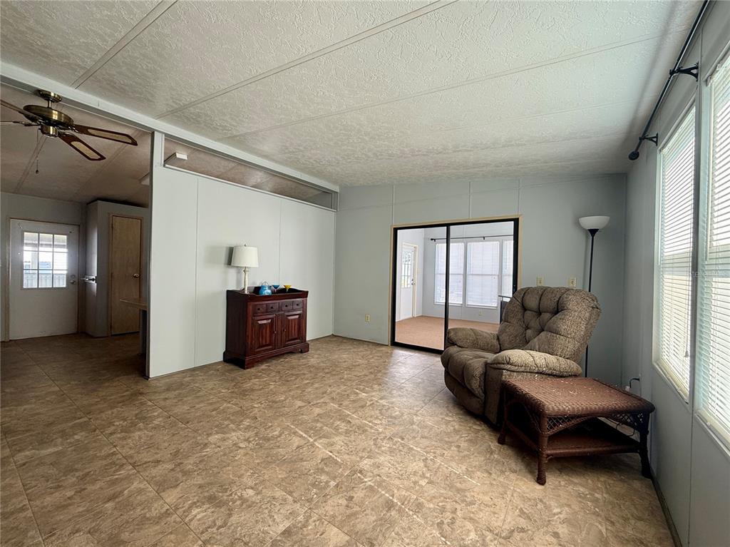 A living room features light-colored walls, tile flooring, a television on a stand, and ceiling fan — 225 N SAINT THOMAS CIRCLE, APOLLO BEACH, FL