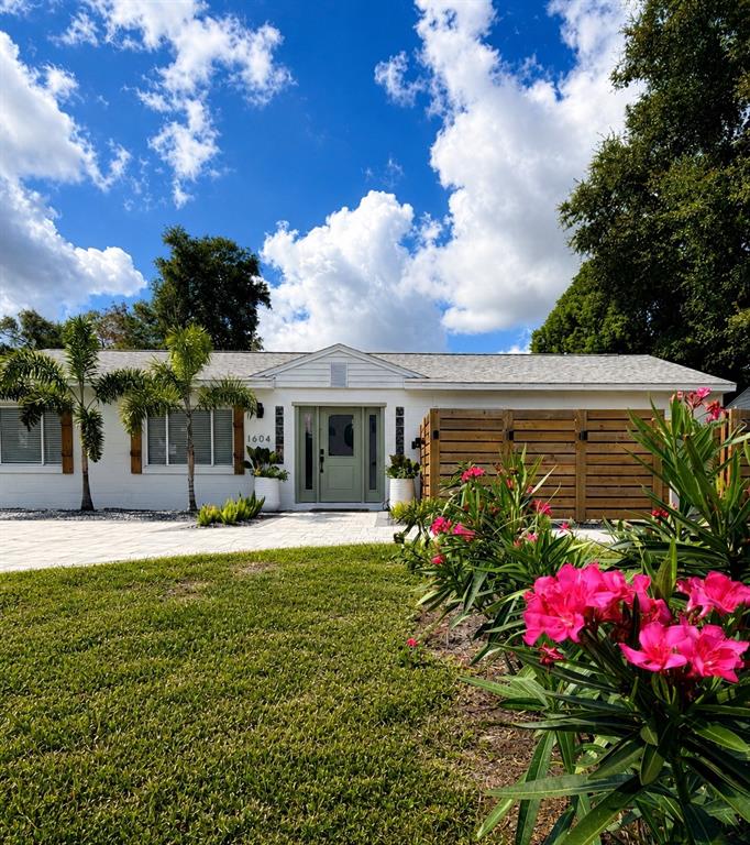 A white single-story house features a sage green front door and a wooden privacy fence — 1604 BRYN MAWR STREET, ORLANDO, FL