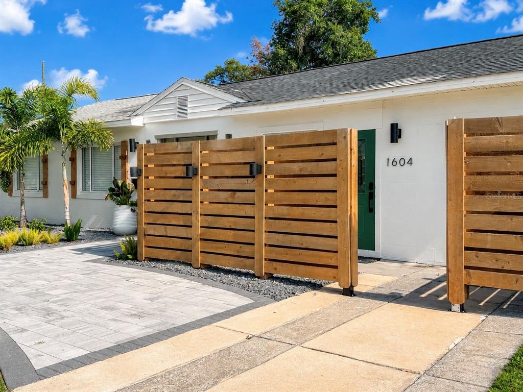 A white house exterior features a horizontal wood slat privacy fence and a green door — 1604 BRYN MAWR STREET, ORLANDO, FL
