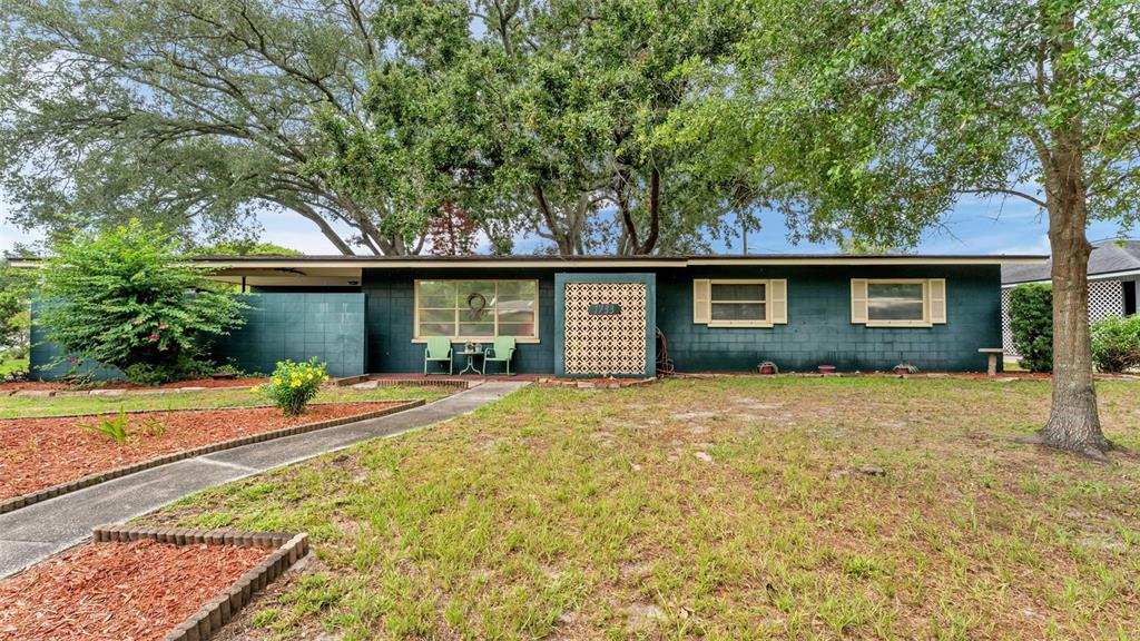 A single-story house with dark green block walls, a lattice screen, and a large tree — 1733 FREDRICKSBURG AVENUE, LAKELAND, FL