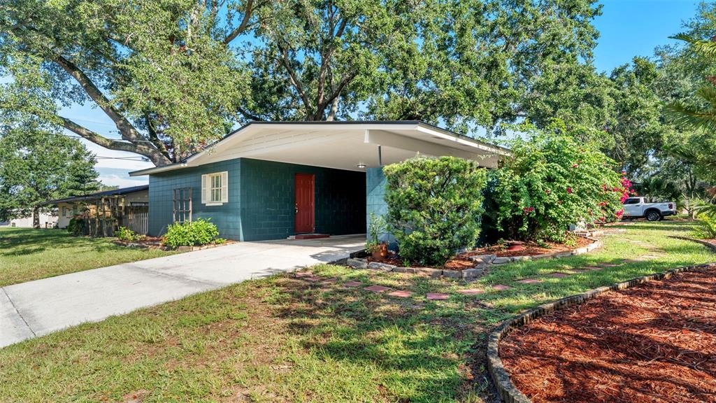 A teal concrete block house features a large carport and a red front door — 1733 FREDRICKSBURG AVENUE, LAKELAND, FL