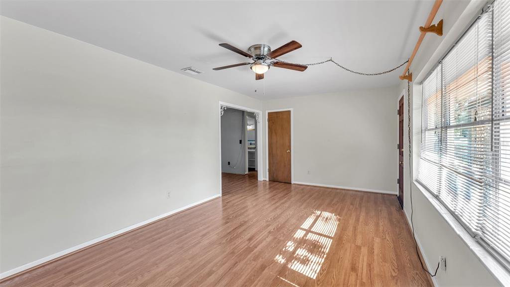 An empty room features light-colored walls, wood-look flooring, a ceiling fan, and a window with blinds — 1733 FREDRICKSBURG AVENUE, LAKELAND, FL