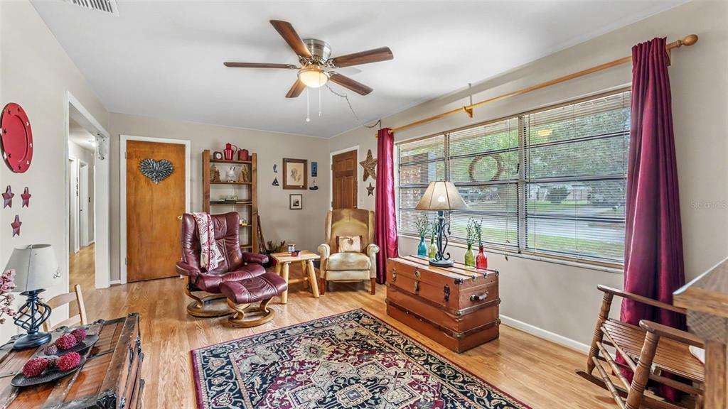 A living room features hardwood floors, a ceiling fan, a patterned rug, and large windows — 1733 FREDRICKSBURG AVENUE, LAKELAND, FL