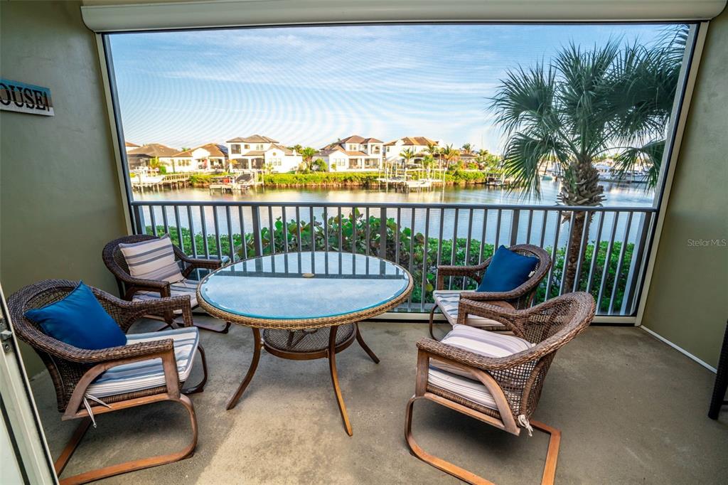 A screened-in balcony features a glass-topped table and four wicker chairs overlooking a canal — 515 BAHIA BEACH BOULEVARD, RUSKIN, FL