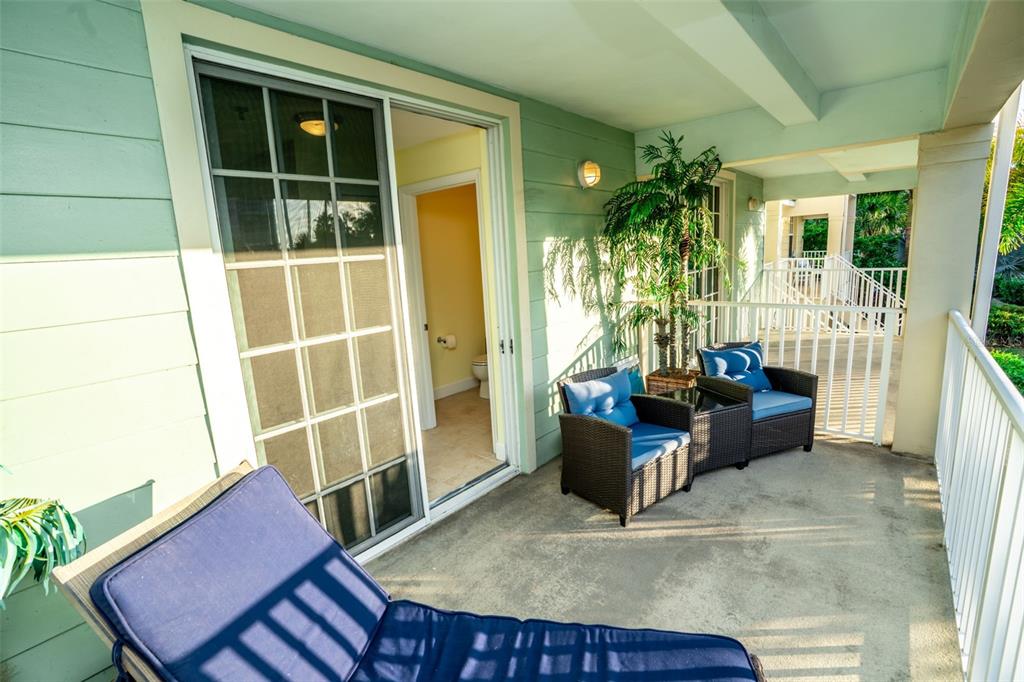 A balcony with wicker chairs, a lounge chair, and a sliding door to a bathroom — 515 BAHIA BEACH BOULEVARD, RUSKIN, FL