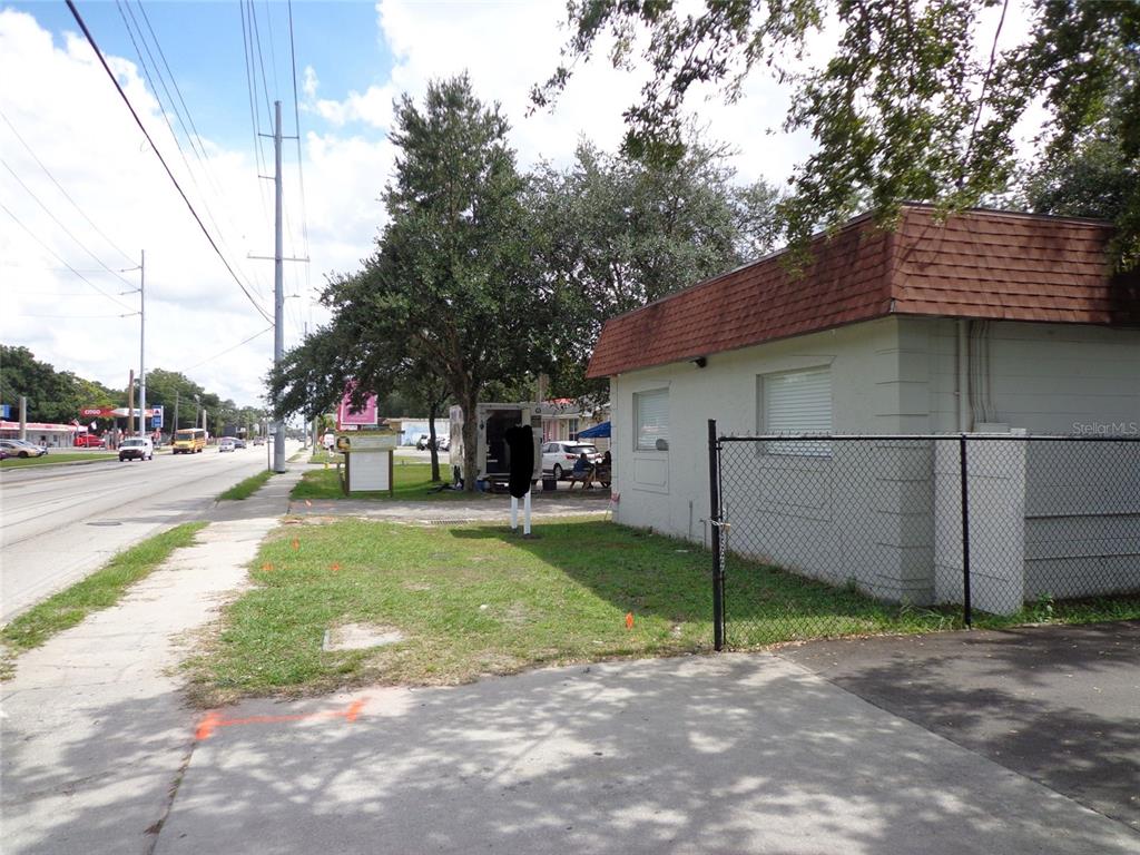 A view of a building exterior with a chain-link fence and a nearby road — 1904 W WATERS AVE, TAMPA, FL
