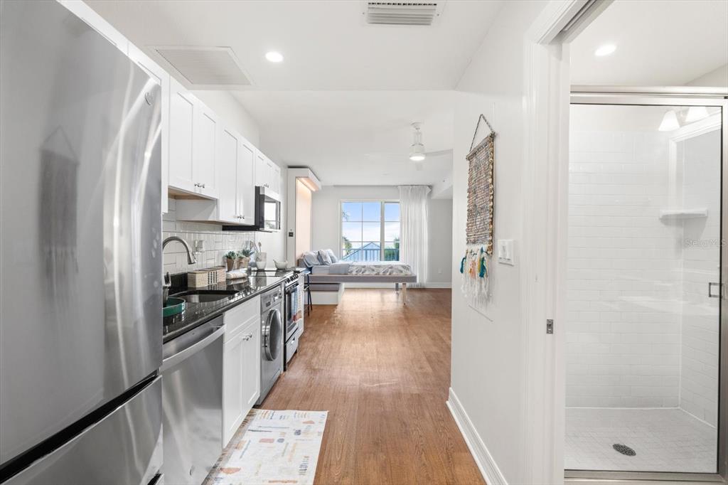 A studio apartment features a kitchen with stainless appliances, wood flooring, and a walk-in shower — 536 BAHIA BEACH BOULEVARD UNIT 320B, RUSKIN, FL