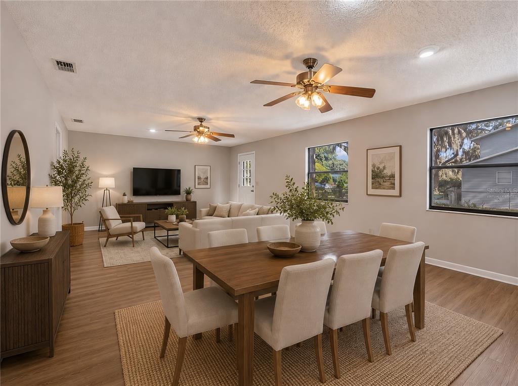 An open-concept living and dining area features wood-look flooring, two ceiling fans, and neutral furniture — 17911 BEACH STREET, UMATILLA, FL