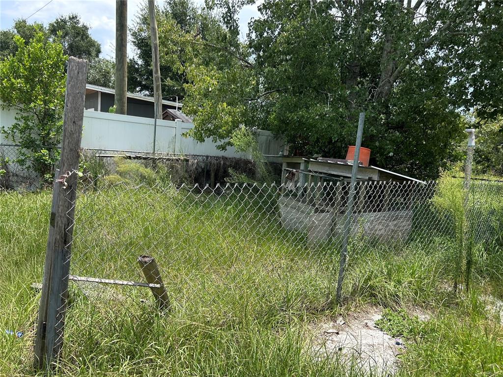 A chain-link fence encloses a grassy yard with a small, weathered shed in the background — 3119 3RD STREET, DAVENPORT, FL