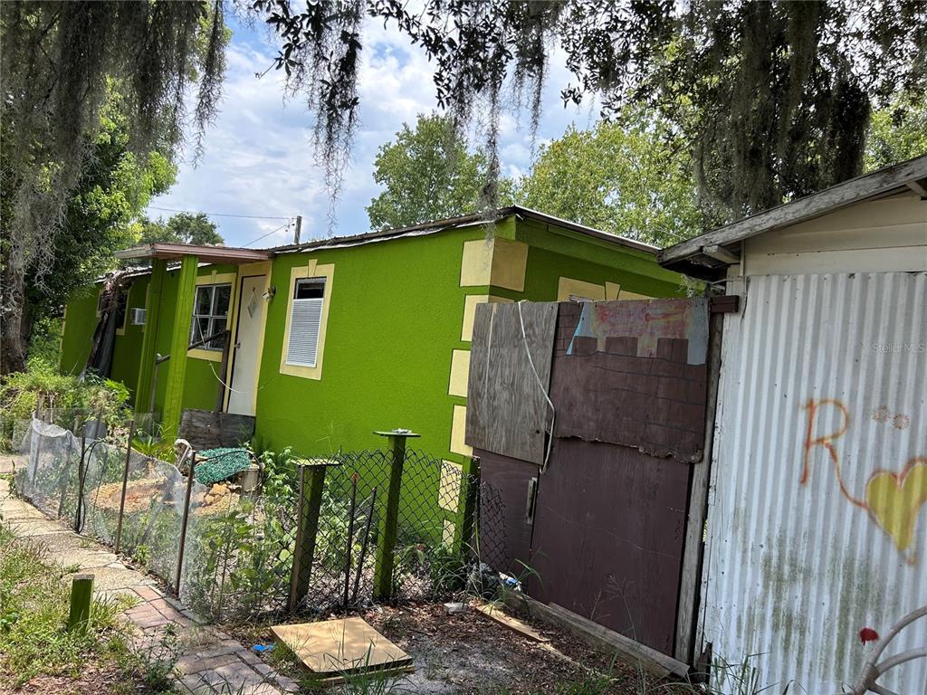 A bright green house with a chain-link fence and a corrugated metal shed exterior — 3119 3RD STREET, DAVENPORT, FL