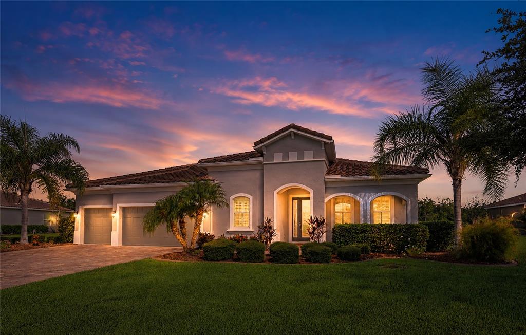 A single-story house with a gray stucco exterior, tile roof, and palm trees at dusk — 16607 2ND AVENUE E, BRADENTON, FL