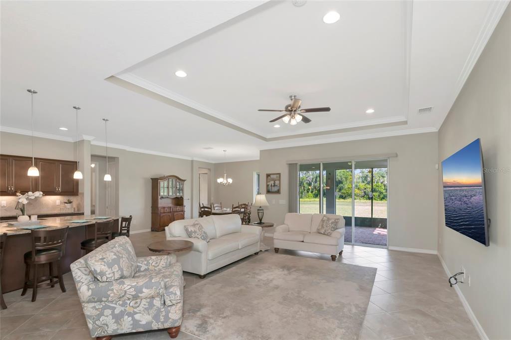 A living room with a tray ceiling, tile floors, and an open-concept kitchen — 16607 2ND AVENUE E, BRADENTON, FL