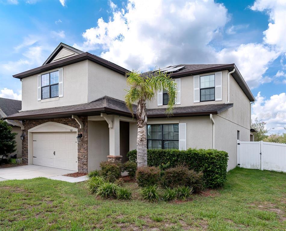 A two-story house with a beige stucco exterior, stone accents, and a two-car garage — 612 SILVERTHORN PLACE, GROVELAND, FL