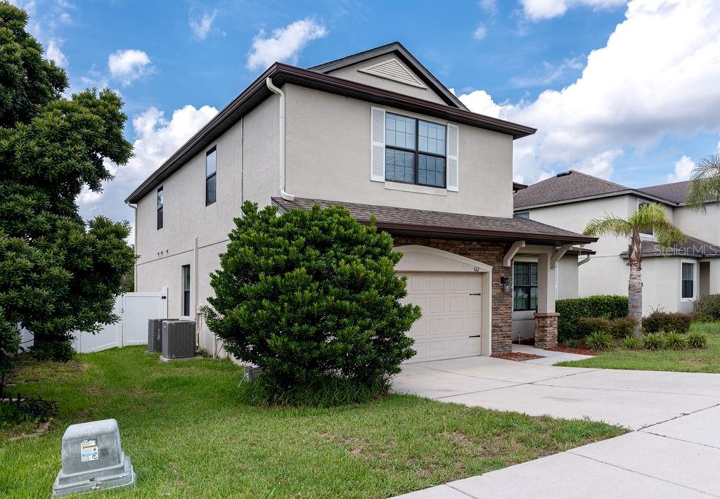 A two-story house with a beige stucco exterior, a stone-accented entryway, and a concrete driveway — 612 SILVERTHORN PLACE, GROVELAND, FL