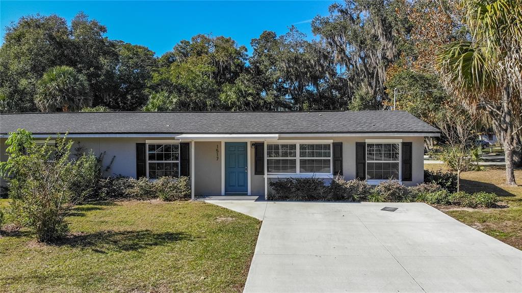 A single-story house with a blue front door, gray exterior, and a concrete driveway — 1517 N GRANDVIEW STREET, MOUNT DORA, FL