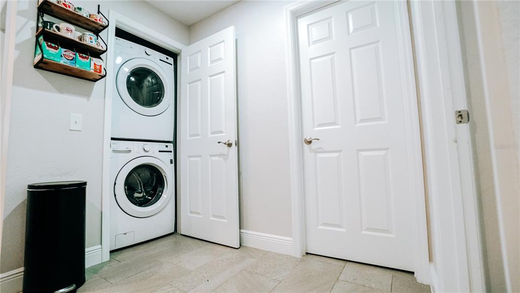 A laundry room features a stacked washer and dryer, a wall shelf, and two white doors — 1517 N GRANDVIEW STREET, MOUNT DORA, FL