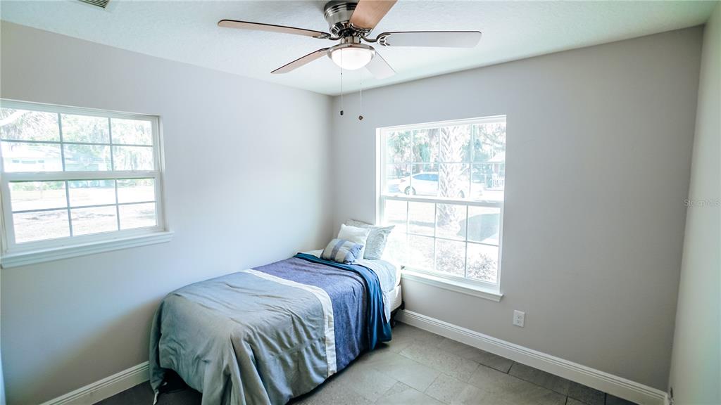 A bedroom with light gray walls, tile flooring, a ceiling fan, and two windows — 1517 N GRANDVIEW STREET, MOUNT DORA, FL