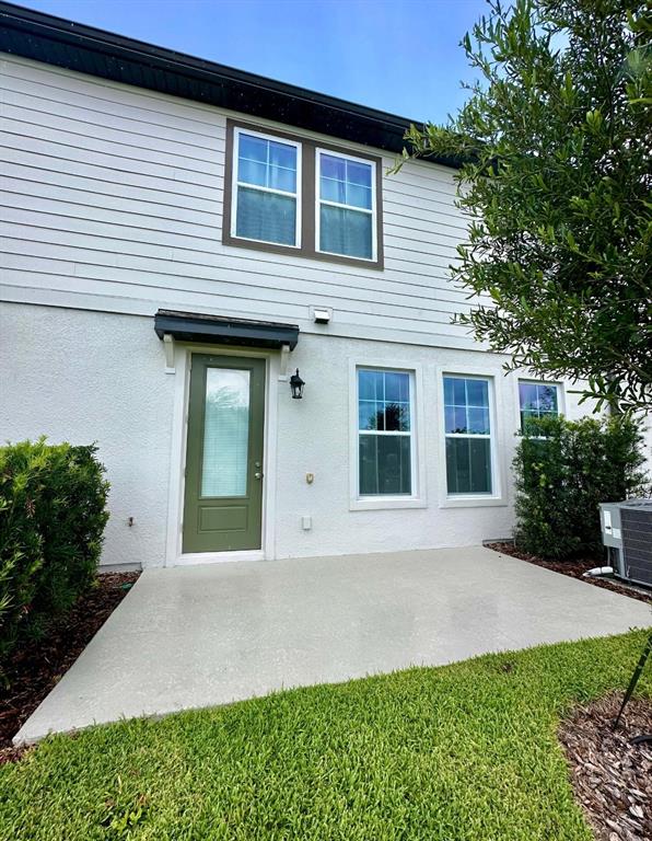 A two-story house exterior features a green door, concrete patio, and white siding — 821 BENOI DR,, DAVENPORT, FL