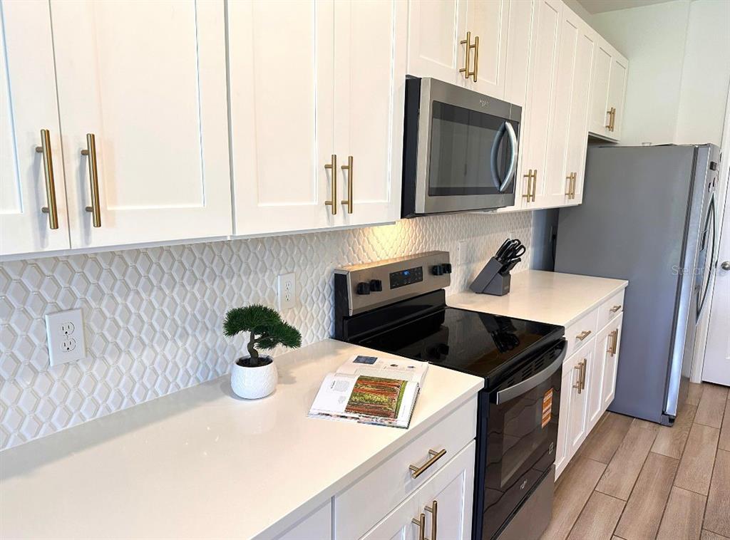 A kitchen features white cabinets, stainless steel appliances, a patterned backsplash, and light countertops — 821 BENOI DR,, DAVENPORT, FL