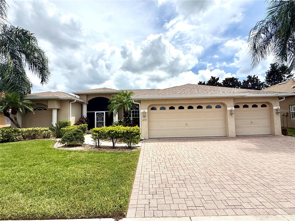 A single-story house with a beige stucco exterior, a three-car garage, and a paved driveway — 3735 GAVIOTA DRIVE, RUSKIN, FL