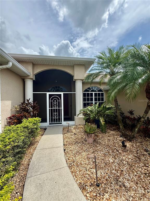 A concrete walkway leads to the screened front entryway of a tan stucco house — 3735 GAVIOTA DRIVE, RUSKIN, FL