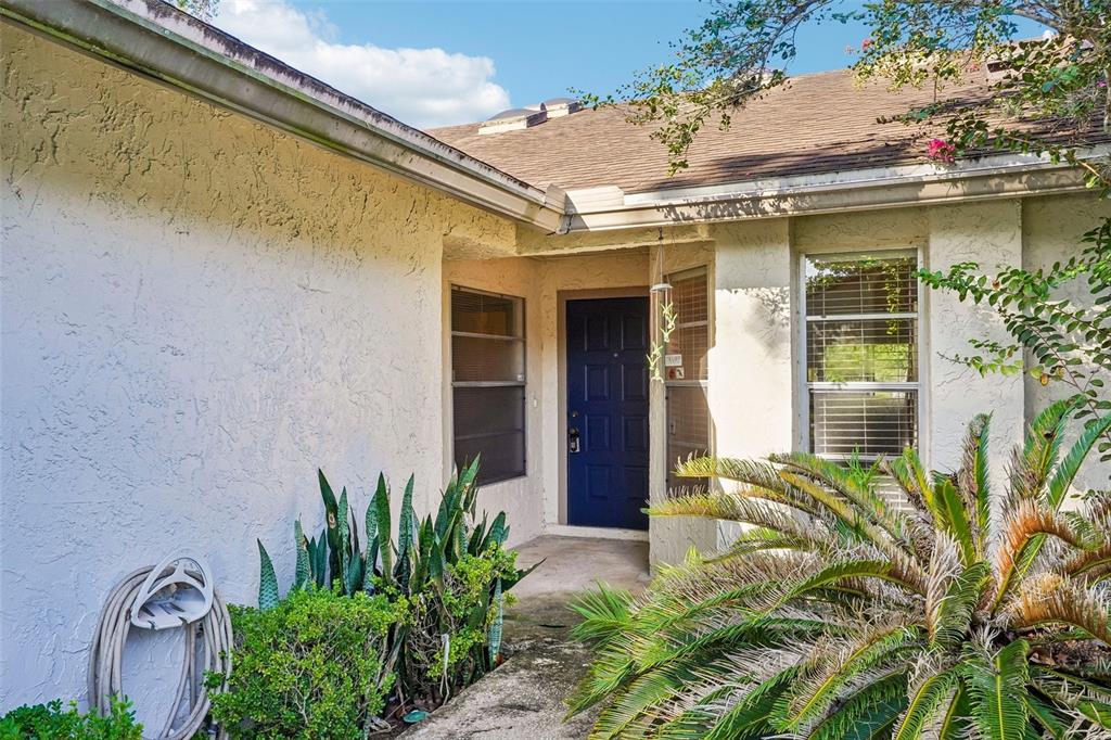 The exterior of a house features a blue front door, stucco walls, and landscaping — 170 HILL STREET, CASSELBERRY, FL