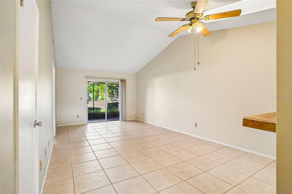 An empty room with vaulted ceilings, tile flooring, a ceiling fan, and sliding glass doors — 170 HILL STREET, CASSELBERRY, FL