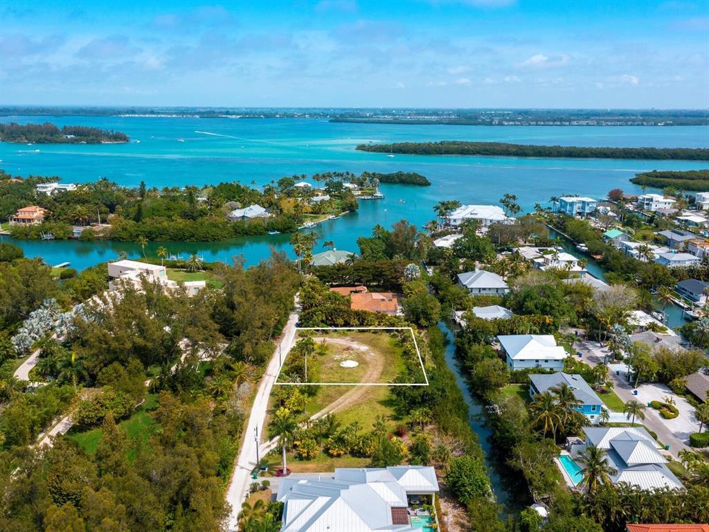 An aerial view shows a vacant rectangular lot surrounded by lush vegetation and nearby waterfront homes — 6604 GULF OF MEXICO DRIVE, LONGBOAT KEY, FL