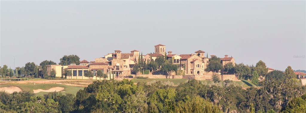 A large stone mansion with multiple towers and a tile roof sits on a golf course — 16103 PENDIO DRIVE, MONTVERDE, FL