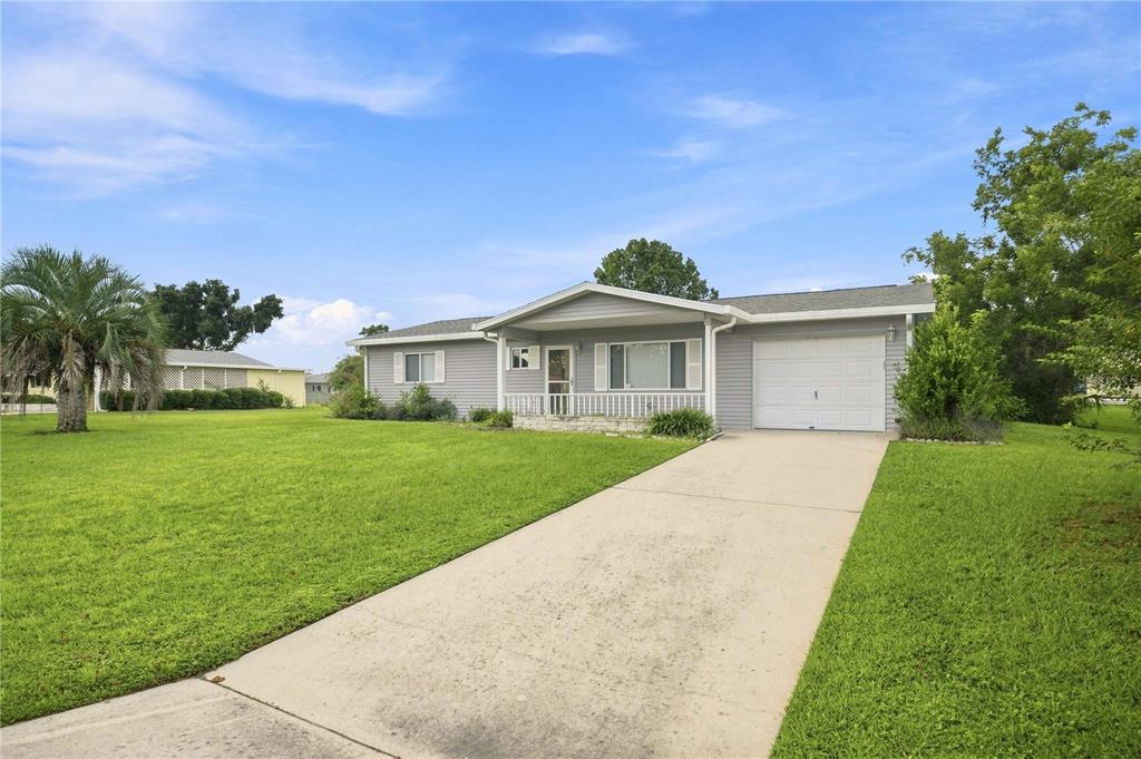 A single-story house with gray siding, a white garage door, and a concrete driveway — 6362 SW 106TH PLACE, OCALA, FL