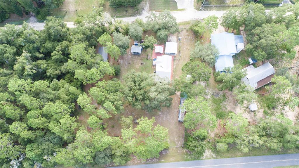 An aerial view shows a wooded property with several buildings and a gravel driveway — 227 NE 838TH STREET, OLD TOWN, FL