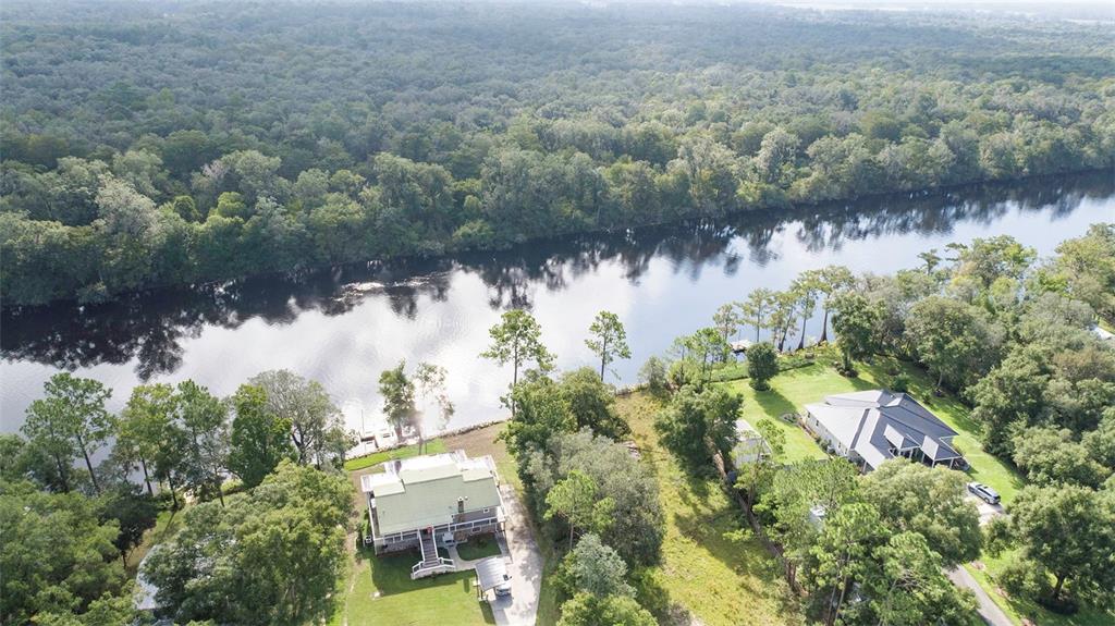 An aerial view shows two houses situated on a grassy lot along a riverbank — 227 NE 838TH STREET, OLD TOWN, FL