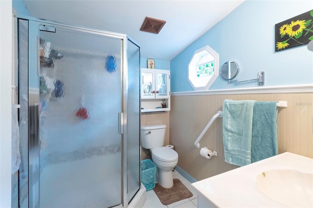 A bathroom features a glass-enclosed shower, a white toilet, and light blue walls with wainscoting — 227 NE 838TH STREET, OLD TOWN, FL