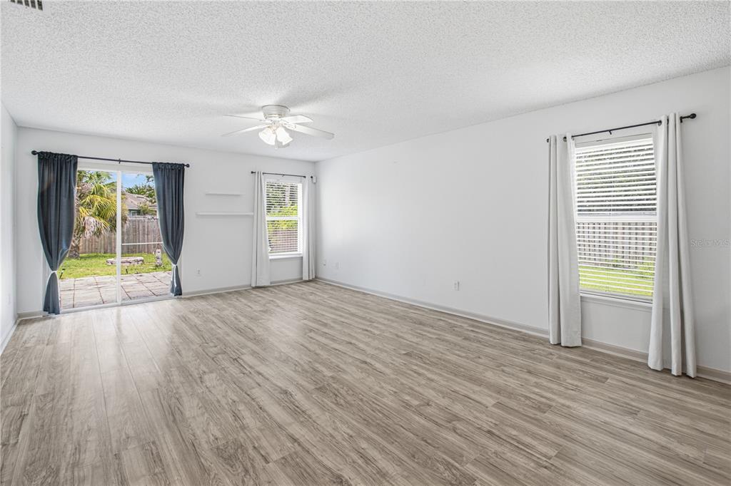 An empty living room features light wood-look flooring, white walls, a ceiling fan, and sliding doors — 736 WYNFIELD CIRCLE, ST AUGUSTINE, FL