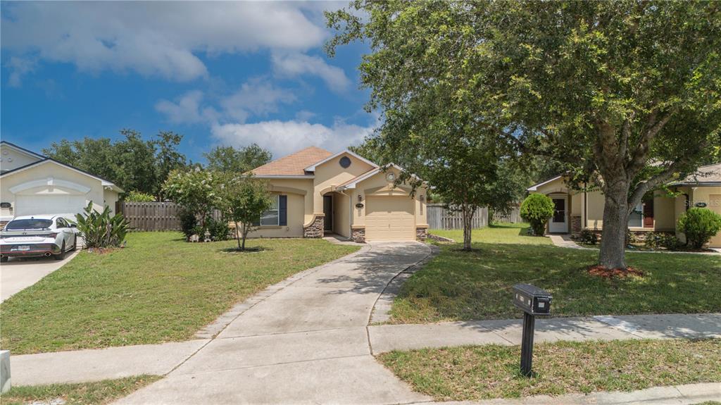 A single-story suburban house with a tan stucco exterior, a one-car garage, and a driveway — 736 WYNFIELD CIRCLE, ST AUGUSTINE, FL