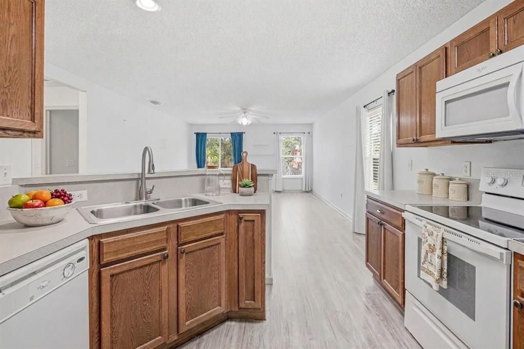 A kitchen with wood cabinets, white appliances, and a sink overlooking an open living area — 736 WYNFIELD CIRCLE, ST AUGUSTINE, FL