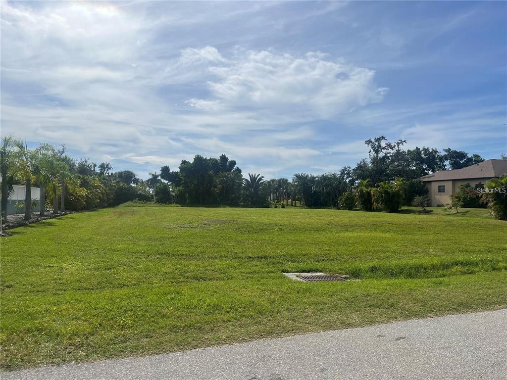 A vacant, grassy residential lot is bordered by trees and a neighboring house — 315 CAPSTAN DRIVE, PLACIDA, FL